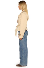 Side view of a cream cropped trench coat with a tied waist belt and buckled cuff straps