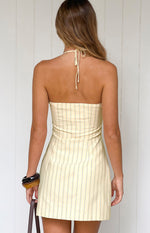 Rear view of a yellow stripe halter neck mini dress with a tied back neck and vertical stripes