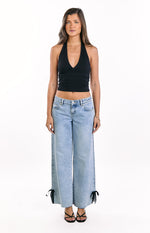 Front view of light wash denim low rise wide leg jeans with black bow tie hems