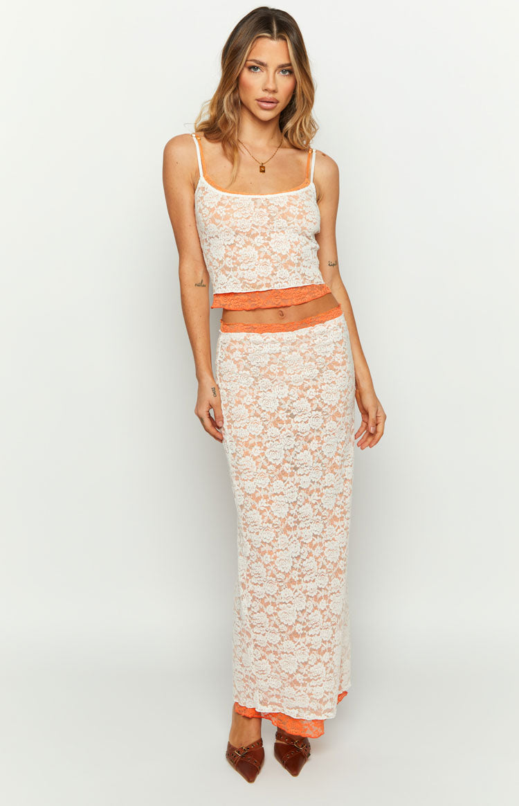 Front view of a white floral lace midi skirt with a fitted silhouette and bright orange lining