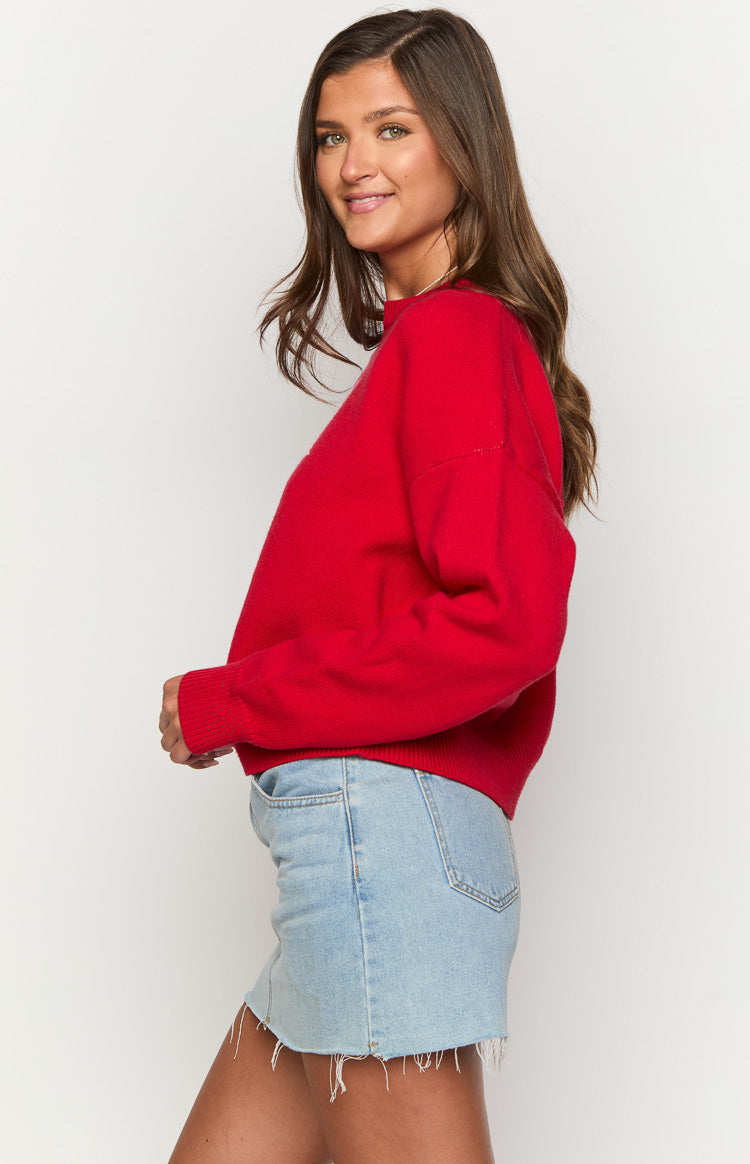 Side view of a bright red relaxed fit sweater with long cuffed sleeves and a ribbed hem