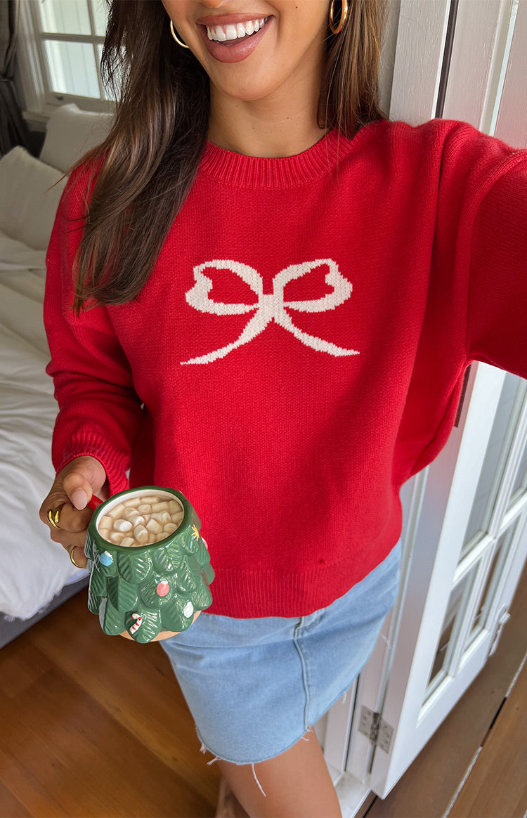 Front view of a red crew neck sweater with a white bow graphic, ribbed cuffs and hem