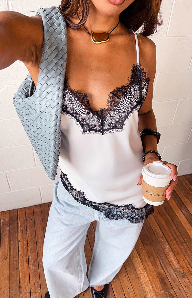 White satin asymmetrical top with black lace trim on the V-neckline and hem
