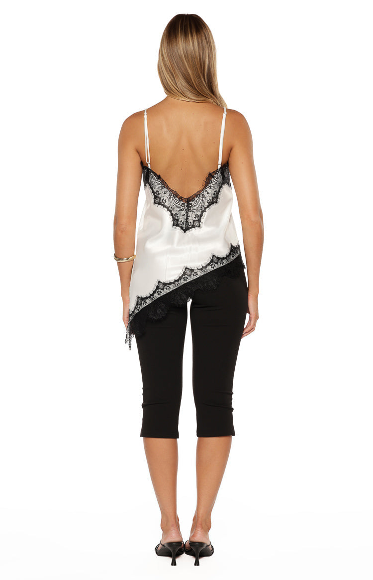 Rear view showing the low V-back of the white satin top with black lace trim and asymmetrical hem