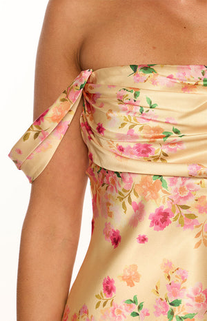 Close-up of the tied off-shoulder sleeve and ruched bodice of a yellow floral mini dress