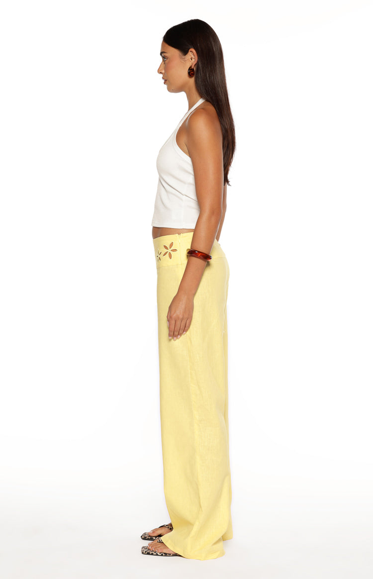 Side view of yellow wide-leg pants with floral cutout detail on the waistband
