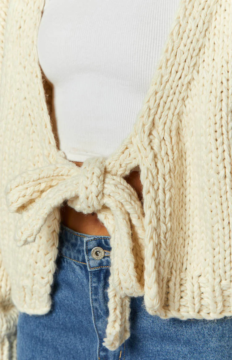 Cream chunky knit cardigan with a tie-up front and voluminous long sleeves, cropped length