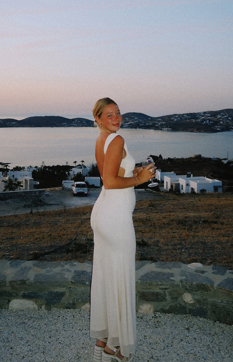 Rear view of a cream mesh maxi dress with an open back and side waist cutouts
