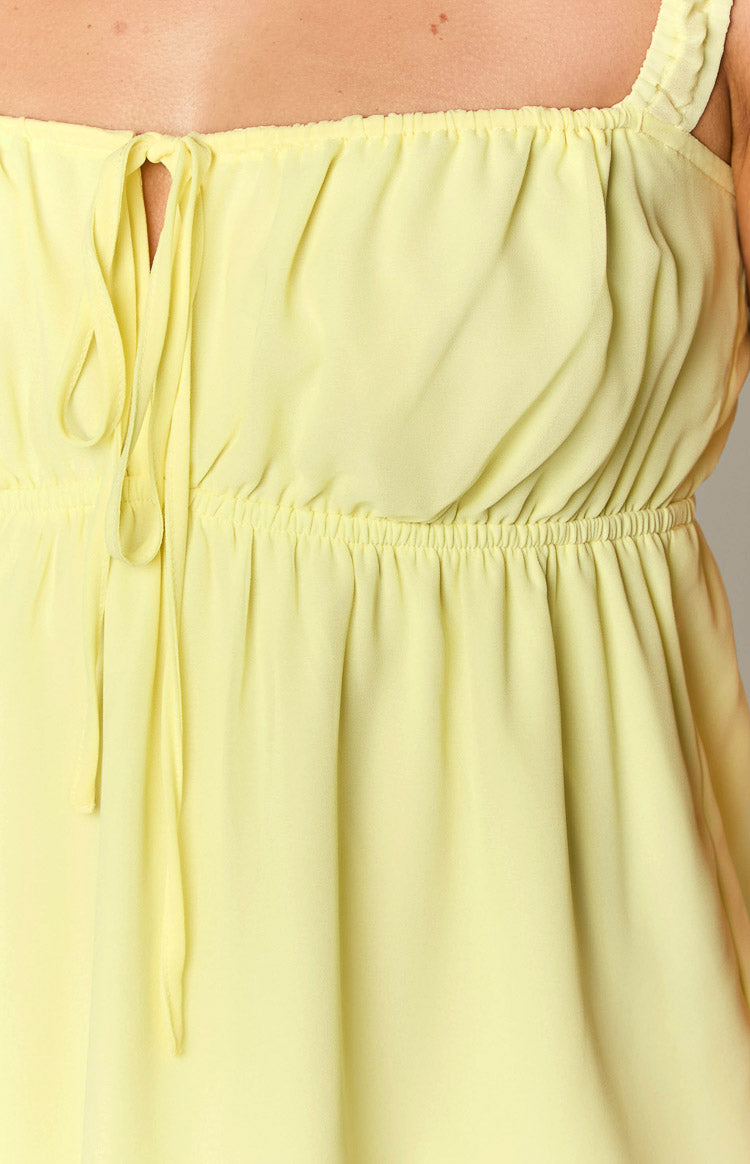 Close-up of the yellow mini dress showing the square neckline with a central drawstring tie and elasticated waist