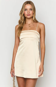 Close-up front view of a cream satin mini dress with a straight neckline and pleated bust