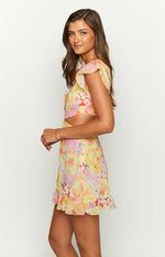 Side view of a yellow floral mini dress with flutter sleeves, waist cutouts, and a ruffled hem