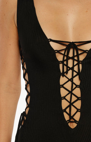 Model in a black ribbed playsuit with a deep lace-up front and side cutouts a daring outfit for a Summer Festival