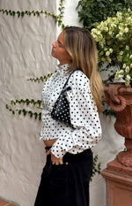 Side view of a white polka dot jacket with a high collar, button front, and long puff sleeves