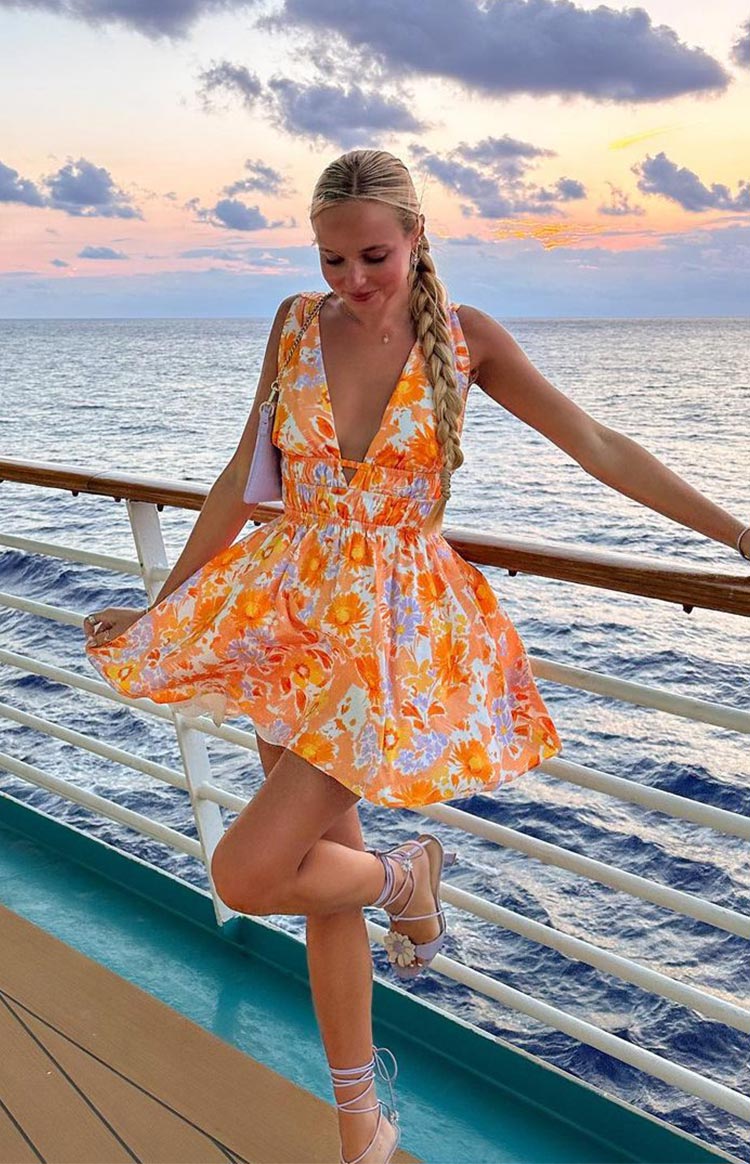 Orange floral mini dress with a deep V-neck, shirred waist, side cutouts, and a flowy skirt