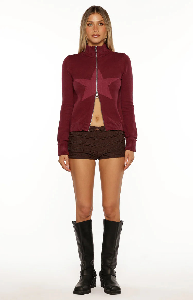Burgundy knit zip-up sweater with a darker burgundy star pattern, high neck, and silver zipper, partially unzipped