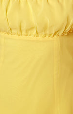 Close-up of the ruched bust detail and ruffled trim on the yellow mini dress