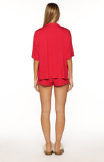 Rear view of a burgundy pajama shirt with a collared neckline and short sleeves, showing its relaxed fit