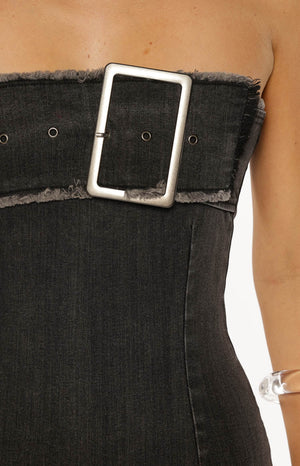 Model kneeling in a black washed denim strapless dress with a large buckle a cool look for a Spring Festival