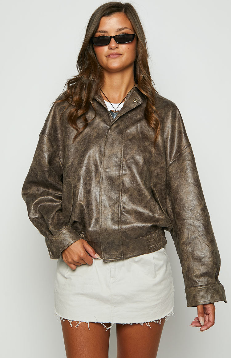 Front view of an oversized chocolate distressed faux leather bomber jacket with a stand collar