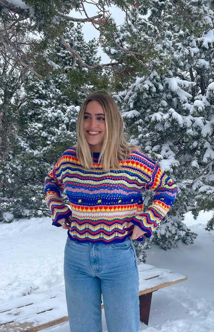Open knit sweater with vibrant multi-coloured stripes and chevron patterns, wide crew neck, long flared sleeves