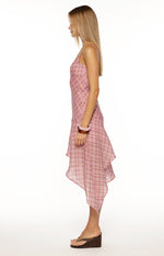 Side view of a pink plaid midi dress with spaghetti straps and a flowy hanky hem skirt