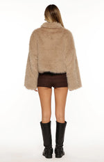 Rear view of a light brown cropped faux fur jacket with a collar and loose long sleeves