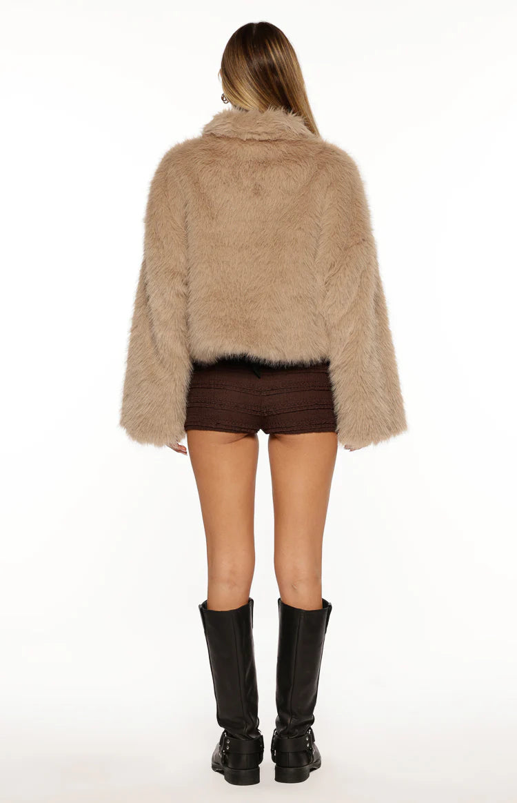 Rear view of a light brown cropped faux fur jacket with a collar and loose long sleeves