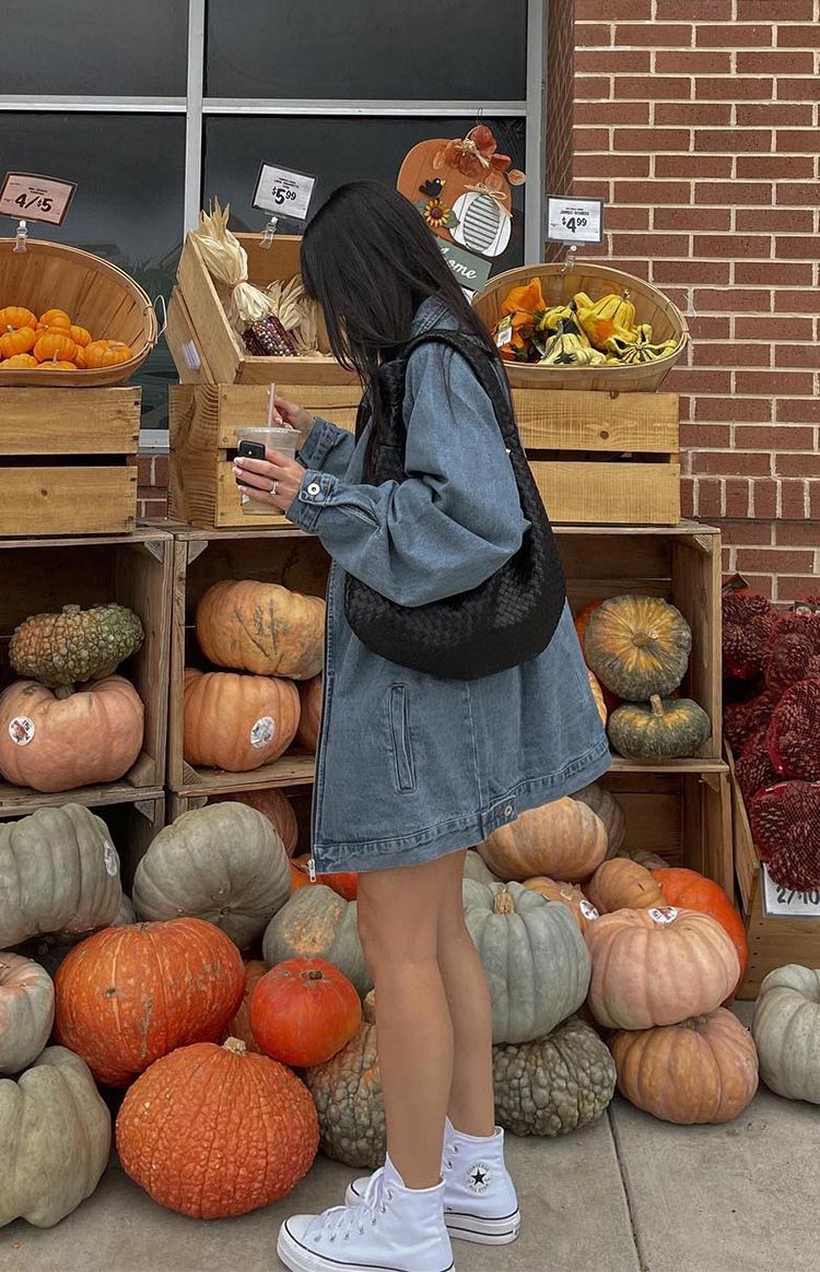Side view of a blue oversized denim jacket with long voluminous sleeves and a full-length zip closure
