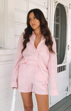 Pink pinstripe shorts with an elasticated waist, paired with a matching long sleeve button-up shirt