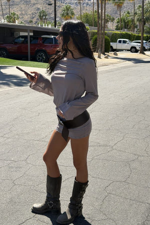 Side view of a brown sheer mesh mini dress with long flared sleeves and stud hem detail
