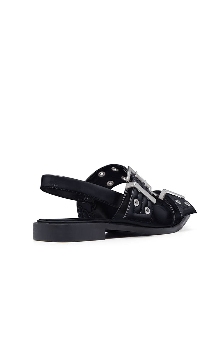 Side view of black patent flats with multiple silver buckles, eyelets, and a slingback strap