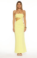 A full-length image of our model wearing a tight strapless yellow maxi dress. This maxi features significant cutouts on the left side of the torso exposing the waist and hip. The skirt of the dress is ruched slightly on the side and flows down to the floor.